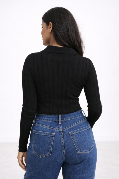 Person wearing a black long-sleeve top and blue jeans on a white background