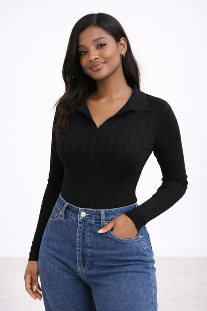 Woman wearing a black long-sleeve top and blue jeans against a white background